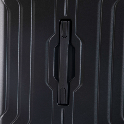 Close-up of a black suitcase handle on a textured black surface
